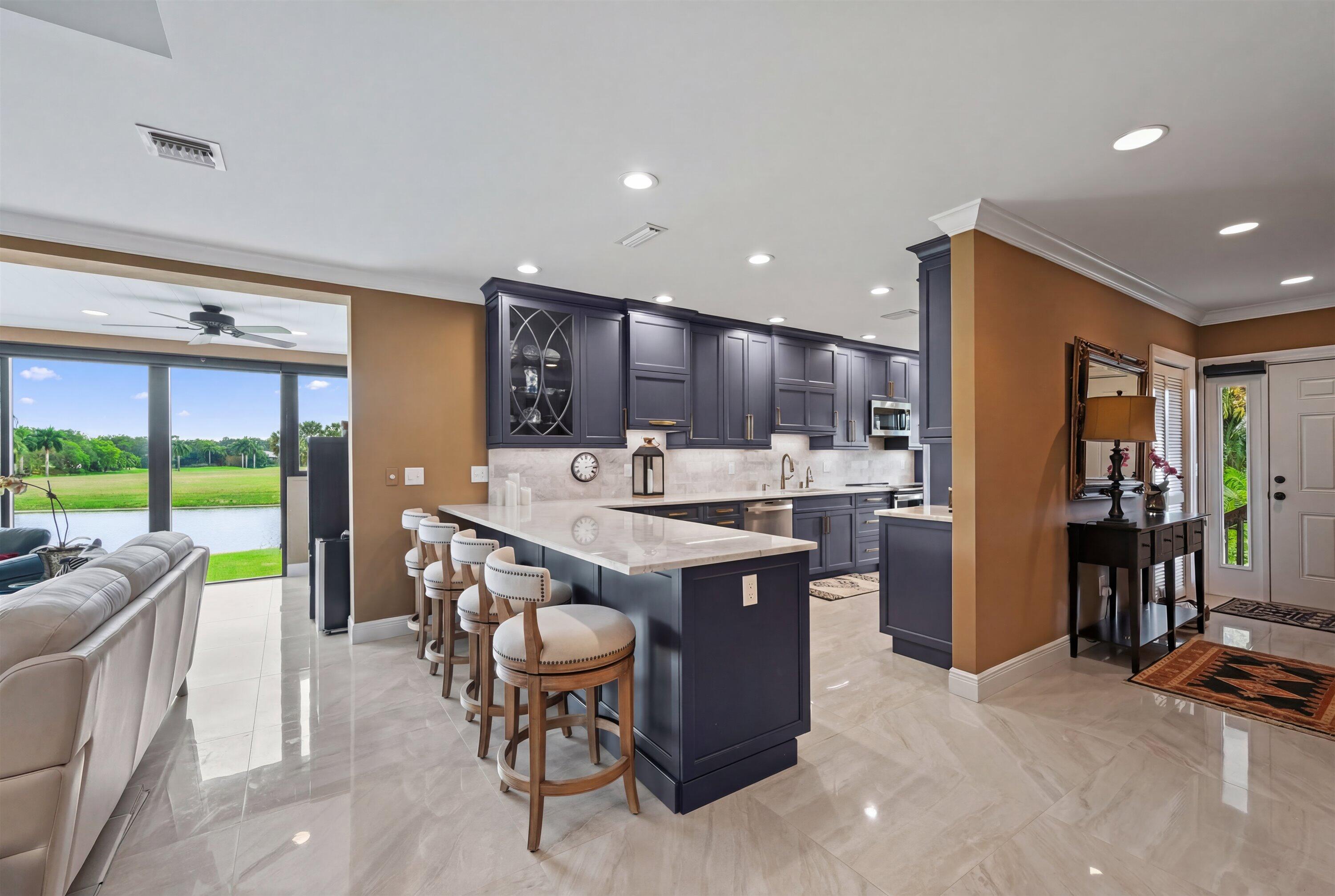 13254 Polo Club Road, Unit C202 Wellington, FL 33414 - Photo 13 of 27 a kitchen with stainless steel appliances kitchen island granite countertop a table chairs and a refrigerator