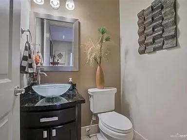a bathroom with a granite countertop toilet sink and mirror