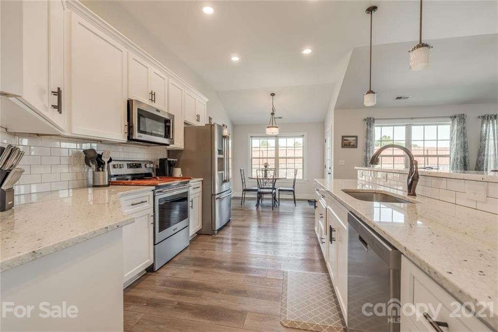 5809 Sikes Mill Road Monroe, NC 28110 - Photo 12 of 32 a kitchen with stainless steel appliances granite countertop a stove a sink a refrigerator and white cabinets with wooden floor
