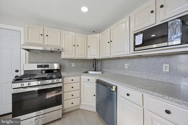 a kitchen with white cabinets and stainless steel appliances