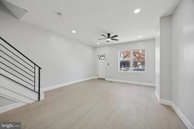 an empty room with windows and chandelier fan
