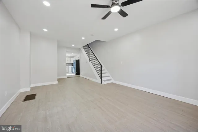 an empty room with a ceiling fan and stairs