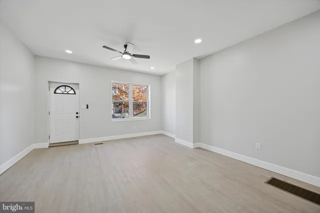 an empty room with ceiling fan and windows
