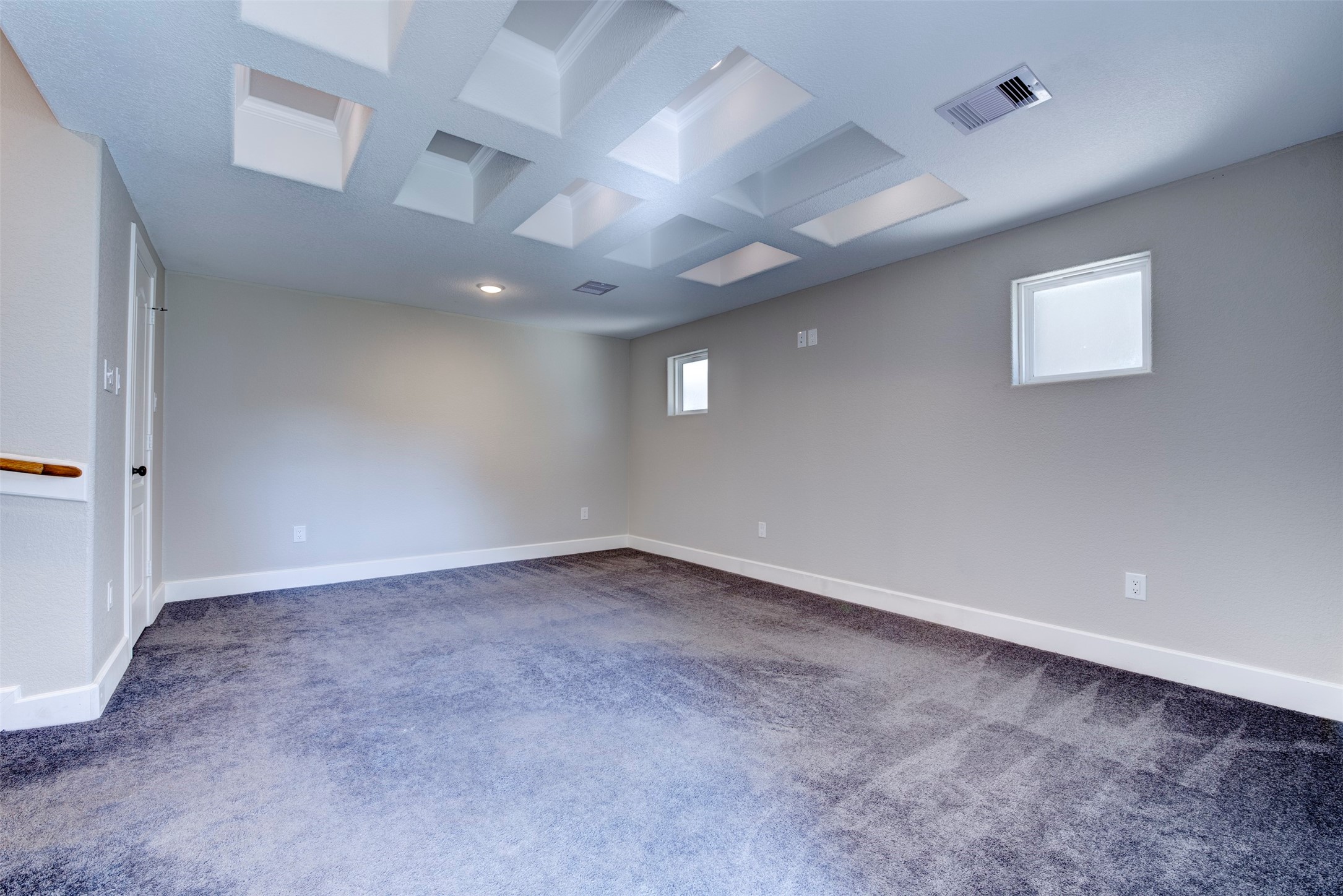 109 Dresden Street Houston, TX 77012 - Photo 24 of 43 Spacious Primary bedroom with neutral walls and carpet, featuring a unique ceiling design with recessed squares and small windows for natural light.