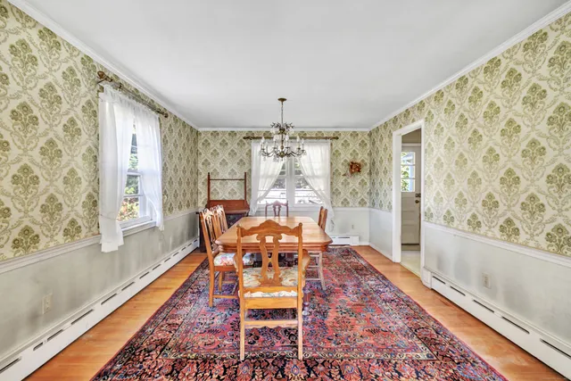 a dining room with wooden floor and large windows