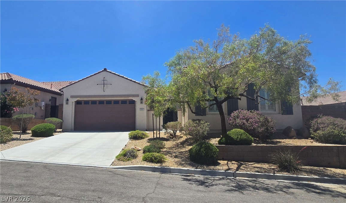 2567 Dirleton Place Henderson, NV 89044 - Photo 4 of 67 Well-maintained desert landscaping frames this inviting residential facade, featuring a practical attached garage and clear blue skies.