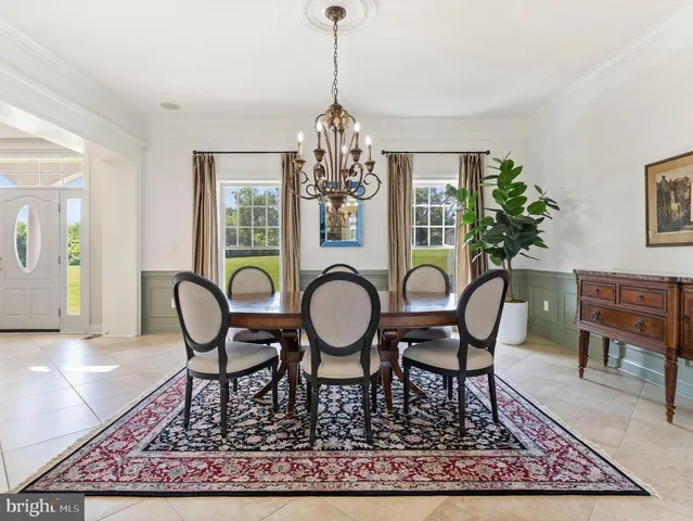 a dining room with chandelier wooden floor and a rug