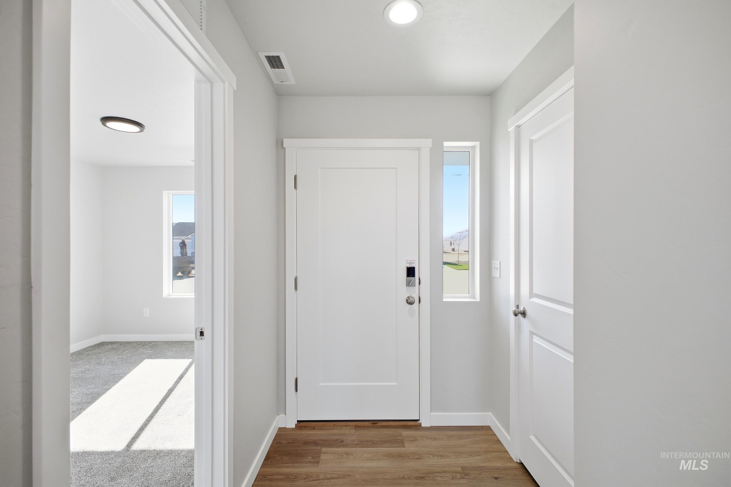 13325 Scrape Street Caldwell, ID 83607 - Photo 2 of 24 Entryway featuring wood-finish flooring, a contemporary white door, and a slim vertical window