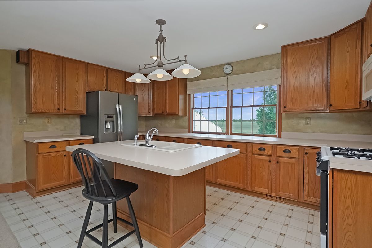 10057 Cherry Valley Road Genoa, IL 60135 - Photo 24 of 32 a kitchen with stainless steel appliances a sink a stove a refrigerator cabinets and dining table