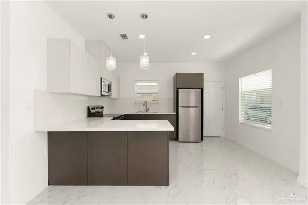 a large kitchen with stainless steel appliances a large counter top a stove a chimney a sink and a refrigerator