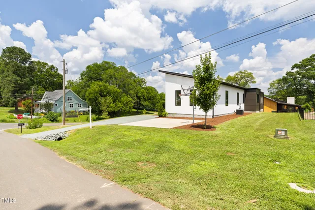 a view of a house with a big yard potted plants and a fountain