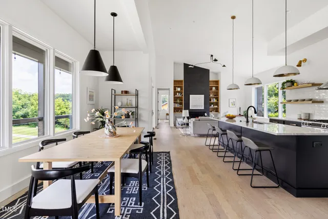a view of a dining room and livingroom furniture wooden floor a chandelier and windows