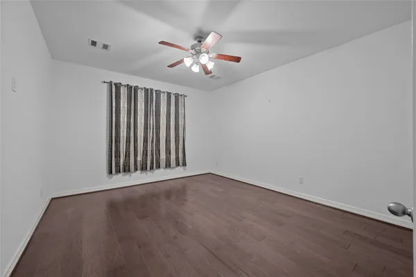 an empty room with wooden floor fan and windows