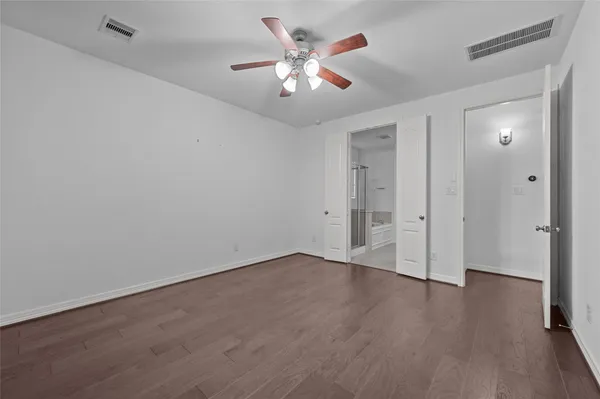 an empty room with wooden floor and ceiling fan