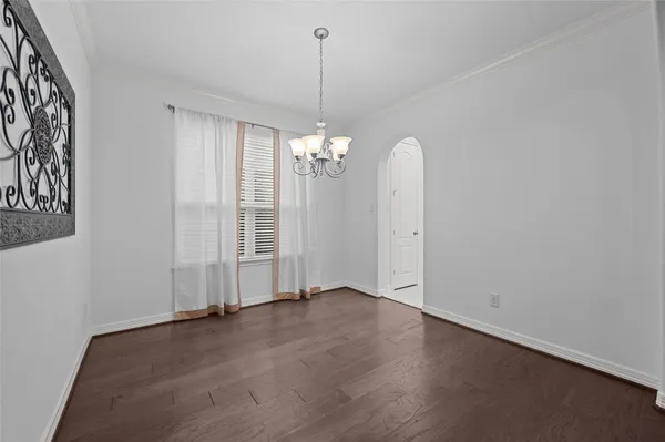 an empty room with chandelier fan and windows