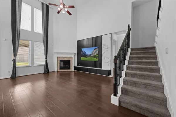 a view of a livingroom with wooden floor a ceiling fan and windows