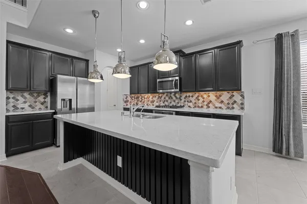 a large kitchen with a sink a counter top stainless steel appliances and cabinets