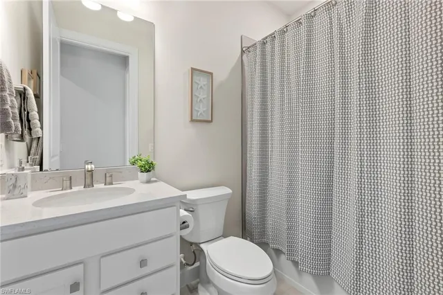 a bathroom with a sink a toilet a mirror and shower curtain