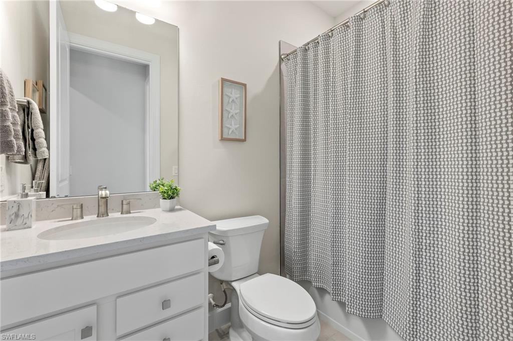 2147 Yellowfin Circle Naples, FL 34114 - Photo 12 of 34 a bathroom with a sink a toilet a mirror and shower curtain