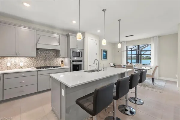 a kitchen with a stove a sink a center island a table and chairs