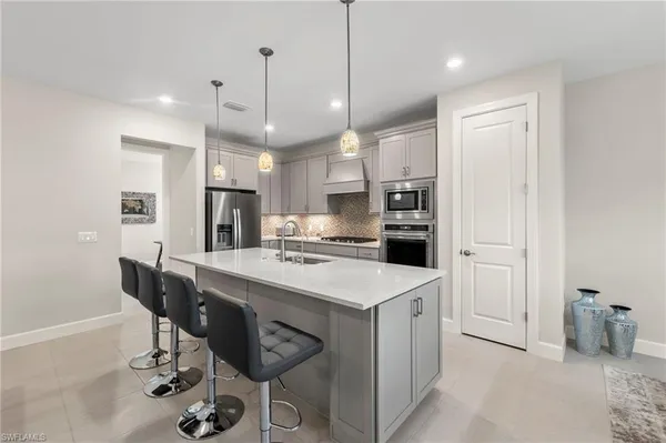 a kitchen with stainless steel appliances kitchen island a table chairs refrigerator sink and microwave