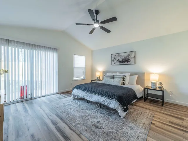 a spacious bedroom with a bed painting on wall and windows