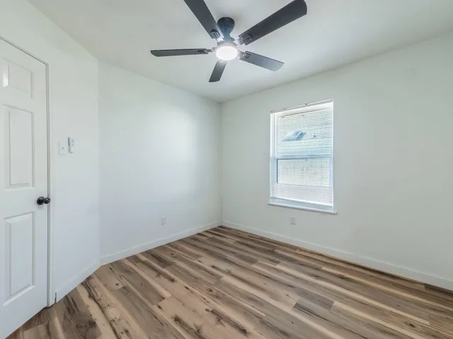 an empty room with a window and a ceiling fan