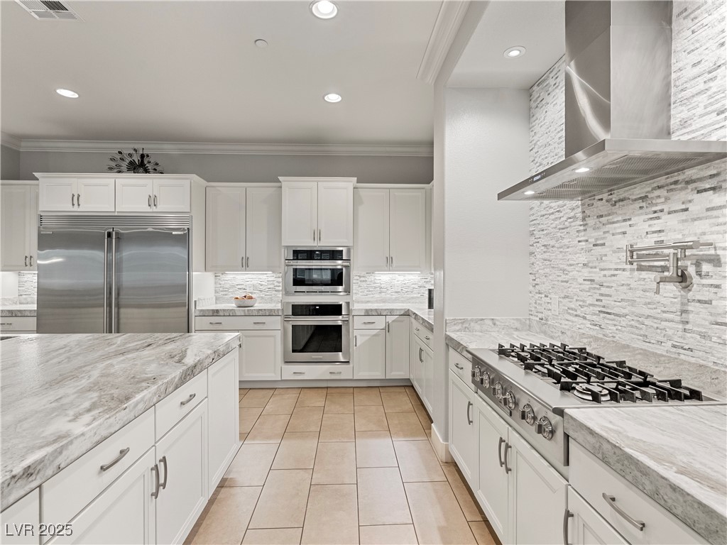 8775 Helena Avenue Las Vegas, NV 89129 - Photo 14 of 72 Kitchen with crown molding, wall chimney exhaust hood, backsplash, white cabinets, and appliances with stainless steel finishes