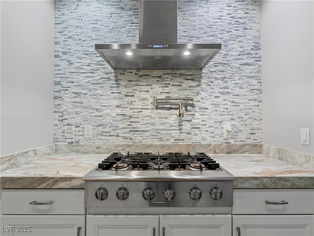 8775 Helena Avenue Las Vegas, NV 89129 - Photo 15 of 72 Kitchen featuring wall chimney range hood, stainless steel gas stovetop, tasteful backsplash, and white cabinetry
