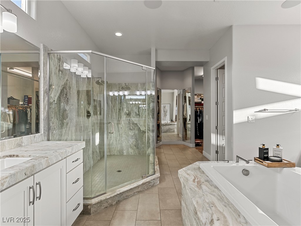 8775 Helena Avenue Las Vegas, NV 89129 - Photo 25 of 72 Full bathroom with a spacious closet, vanity, light tile patterned flooring, and a garden tub