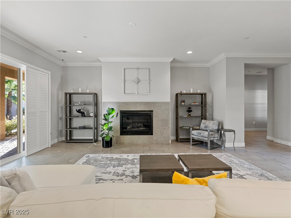 8775 Helena Avenue Las Vegas, NV 89129 - Photo 8 of 72 Living room featuring crown molding, a tiled fireplace, stone tile flooring, and recessed lighting