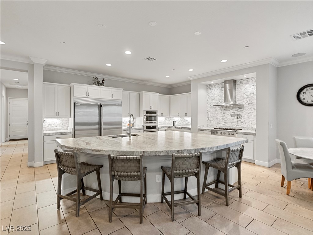 8775 Helena Avenue Las Vegas, NV 89129 - Photo 10 of 72 Kitchen featuring tasteful backsplash, crown molding, white cabinetry, a spacious island, and stainless steel appliances