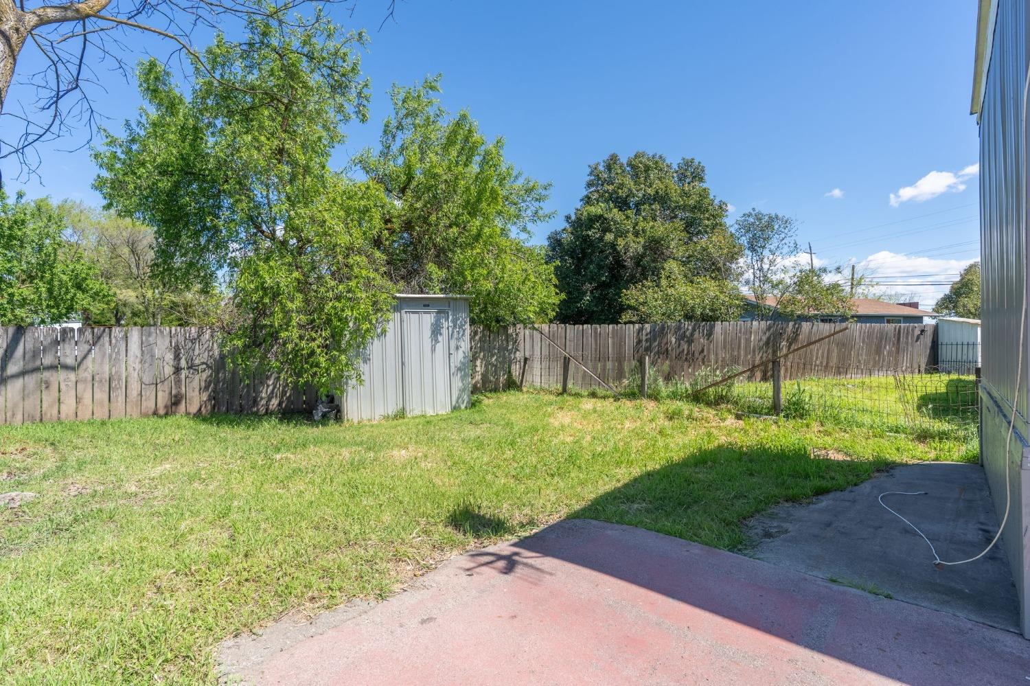 5835 Cherokee Road, Unit 7 Stockton, CA 95215 - Photo 15 of 16 a view of a backyard with large trees and wooden fence