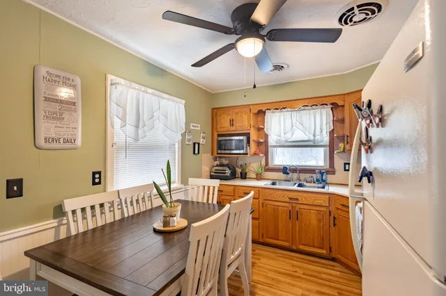 a kitchen with stainless steel appliances kitchen island granite countertop a table chairs in it and wooden floors