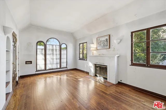 a view of an empty room with window wooden floor and fire place