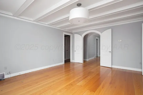 a view of an empty room with wooden floor and stairs