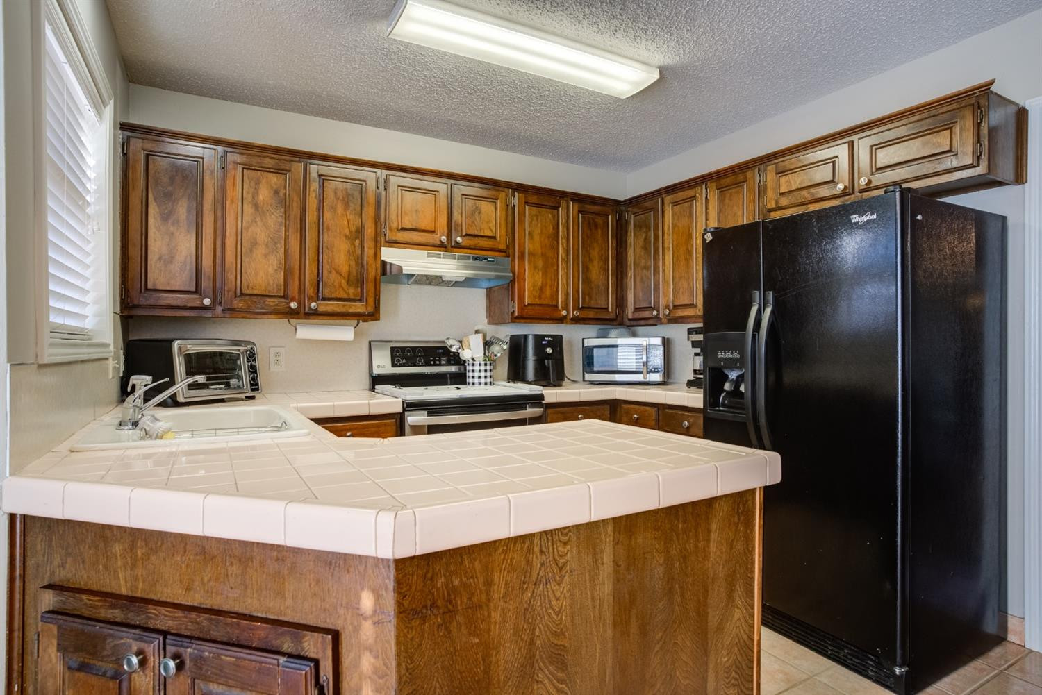 3409 103rd Street Lubbock, TX 79423 - Photo 9 of 33 a kitchen with a refrigerator a stove a sink and a cabinets