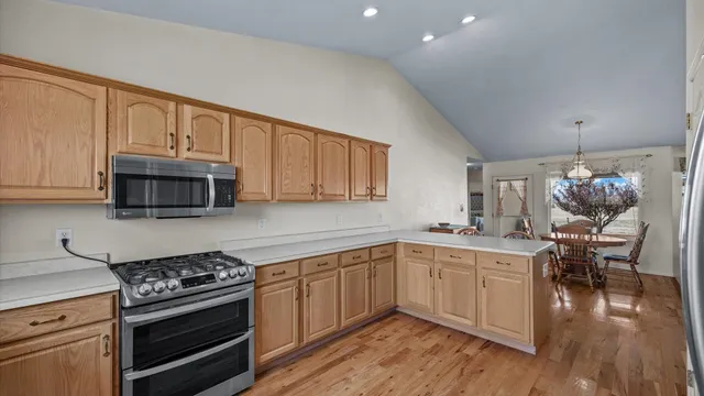 a kitchen with stainless steel appliances a stove a sink cabinets and a wooden floor