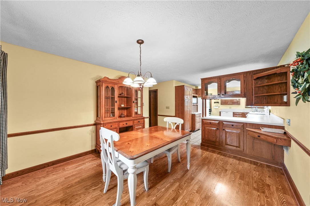 10 Kehner Road Mogadore, OH 44260 - Photo 5 of 32 Dining area with an inviting chandelier, hardwood / wood-style flooring, sink, and a textured ceiling