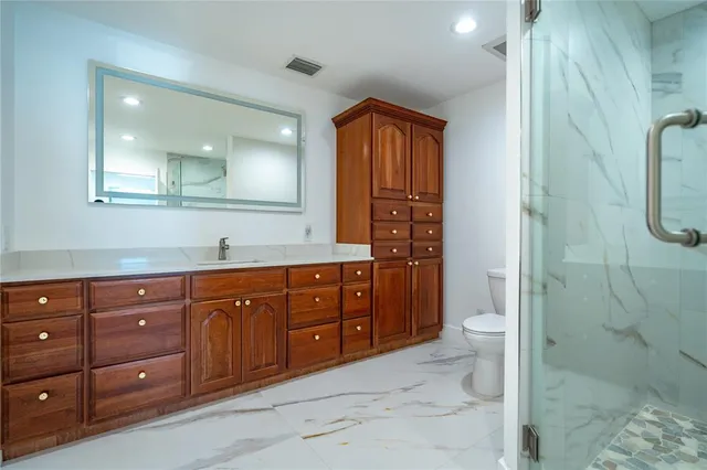 a bathroom with a granite countertop sink a toilet and shower