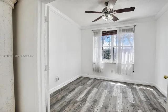 a view of empty room with wooden floor and fan