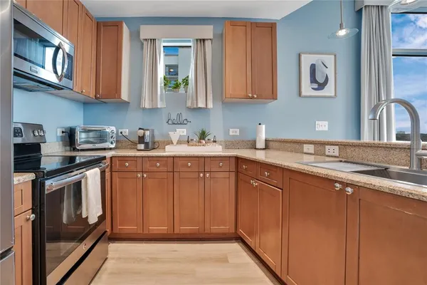 a kitchen with stainless steel appliances granite countertop a refrigerator a stove top oven a sink dishwasher and white cabinets with wooden floor