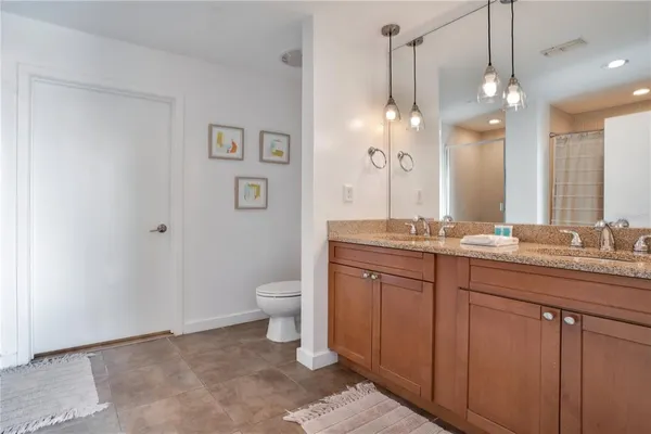 a bathroom with a granite countertop sink a toilet a mirror a vanity and shower