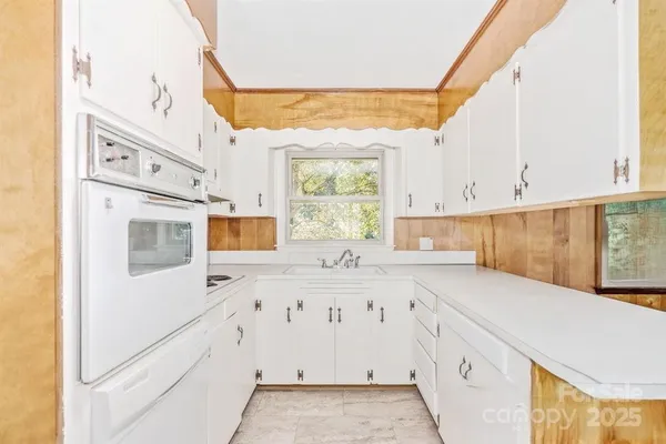 a kitchen with granite countertop white cabinets and window