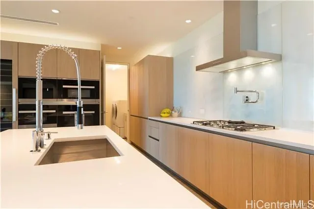 a large white kitchen with stainless steel appliances granite countertop a sink and a stove