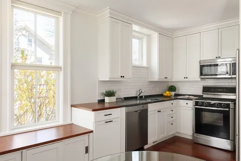 a kitchen with granite countertop white cabinets and a window