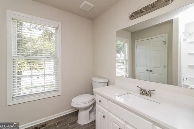 a bathroom with a toilet a sink a mirror and a window