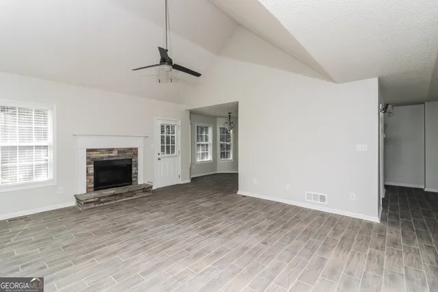 an empty room with windows and fireplace