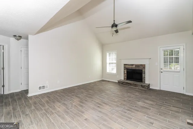 an empty room with windows fireplace and a sink