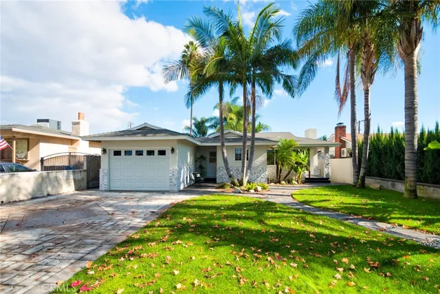 a view of a house with a yard and palm trees